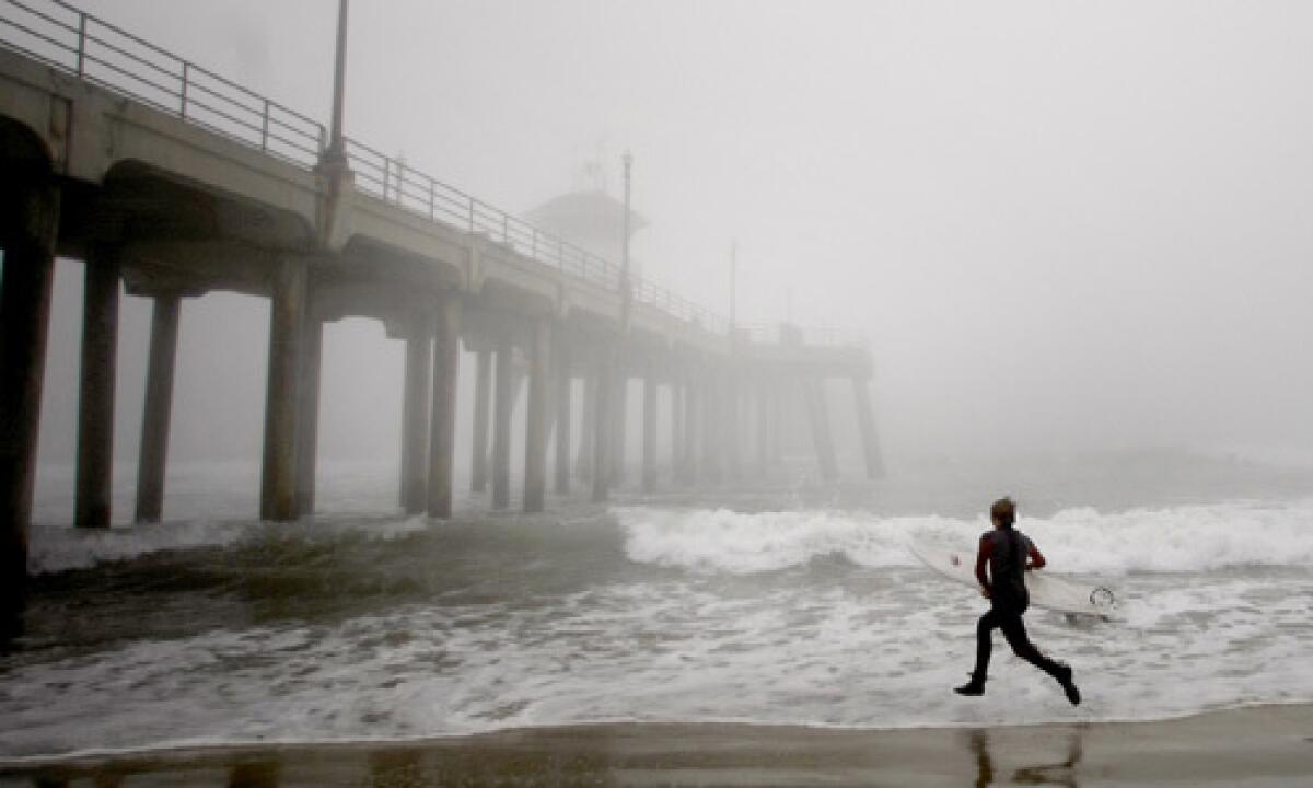 The breaking waves and the fog don't dampen the enthusiasm of Derek Baldwin, 14, of Westminster, as he runs into the surf by the Huntington Beach pier.