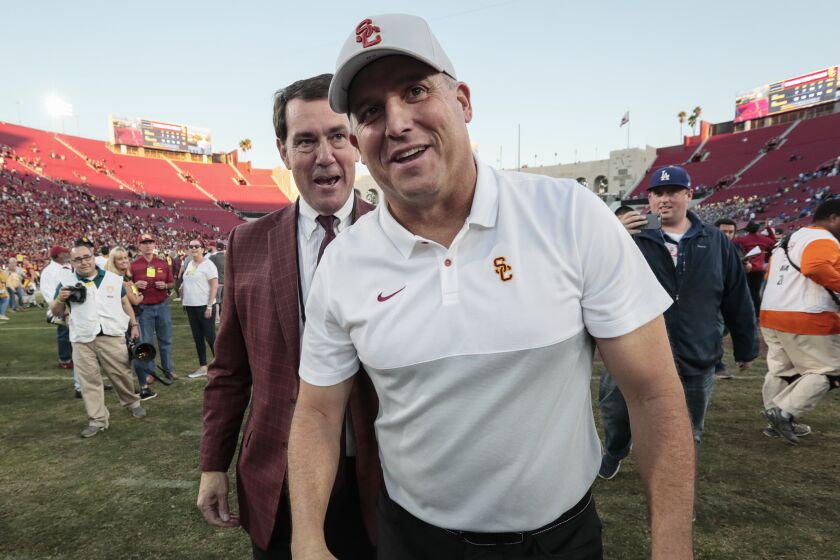 USC coach Clay Helton and athletic director Mike Bohn share a laugh together at midfield after a 52-35 win over UCLA at the Coliseum.