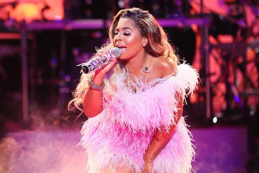 Ashanti singing onstage in a frilly pink dress