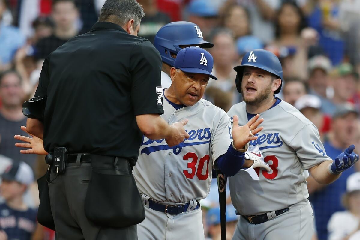 Dodgers manager Dave Roberts steps between Max Muncy and home plate umpire Jordan Baker.