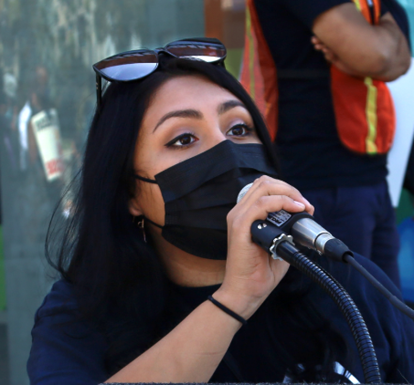 Yesenia Barrera, a former Amazon packer, speaks into a microphone.