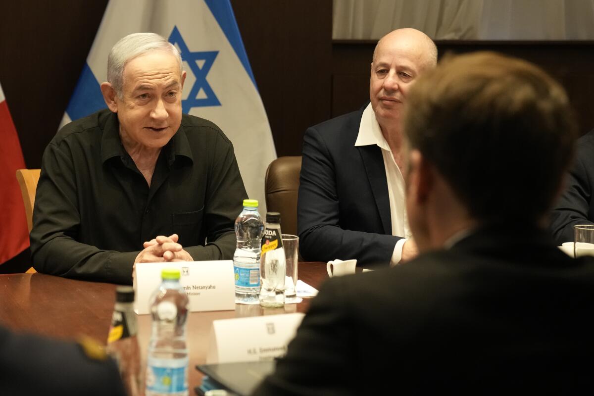 Benjamin Netanyahu sits across a table from Emmanuel Macron