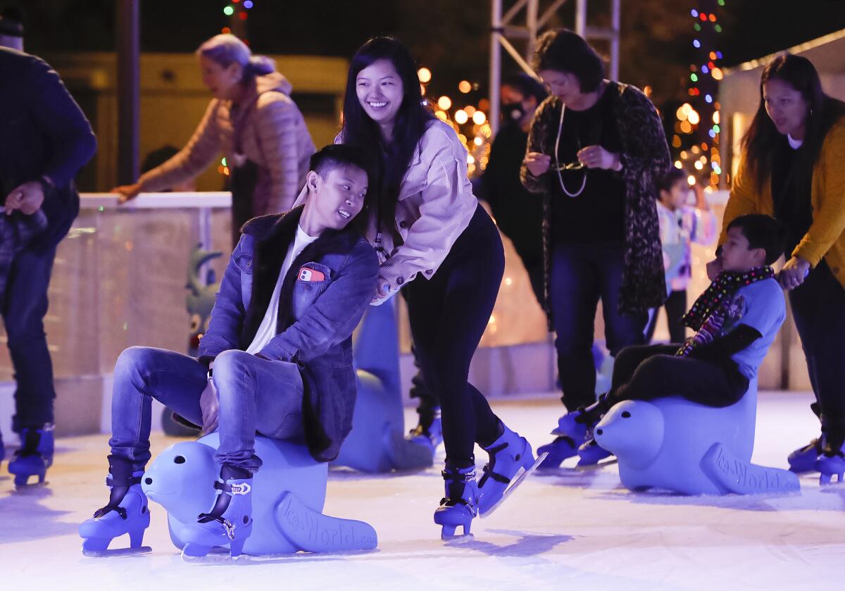 Mary and Kevin Yoon slide on a seal sled at the Santa Ana Winter Village ice-skating rink in Santa Ana.