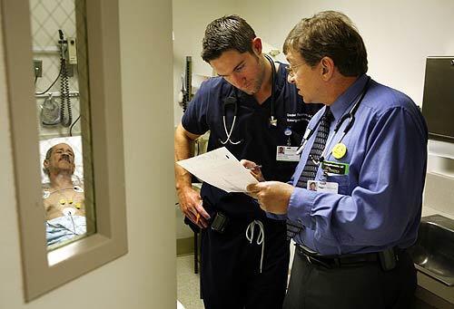In UC Irvine Medical Center's emergency room in Orange, department Director Dr. Mark Langdorf, right, confers with Dr. Daniel Thompson about Michael Recoud, who is suffering from extremely high blood pressure. When Langdorf began practicing emergency medicine more than 20 years ago, finding a specialist to help with a complicated case was easy. But today, specialists are much harder to find in many emergency rooms.
