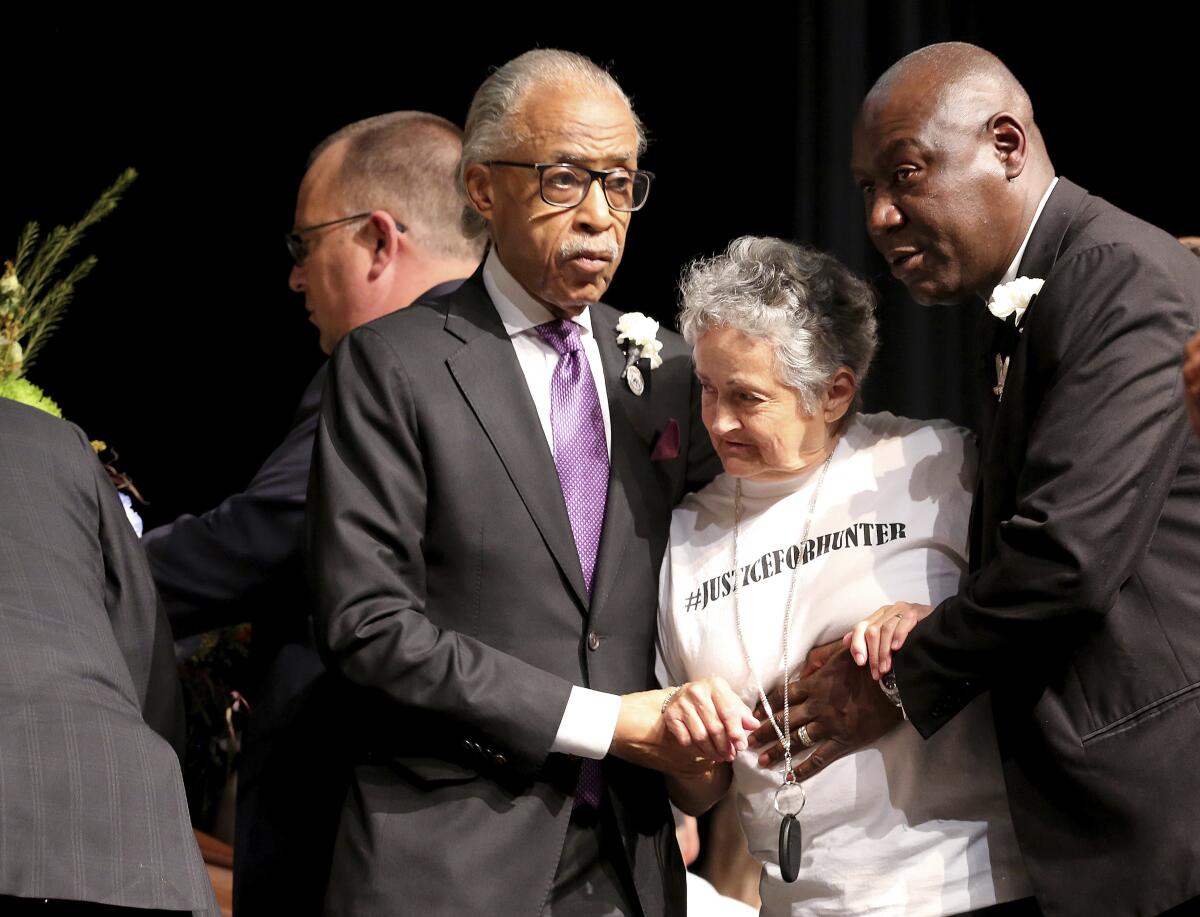 Rev. Al Sharpton, left, and attorney Benjamin Crump, right, escort Rebecca Payne to view her grandson's casket during the funeral service for 17-year-old Hunter Brittain, on Tuesday, July 6, 2021, at the Beebe High Schools Auditorium in Beebe, Ark. Brittain was shot by a Lonoke County Sheriff's Deputy during a traffic stop on June 23. (Tommy Metthe/The Arkansas Democrat-Gazette via AP)