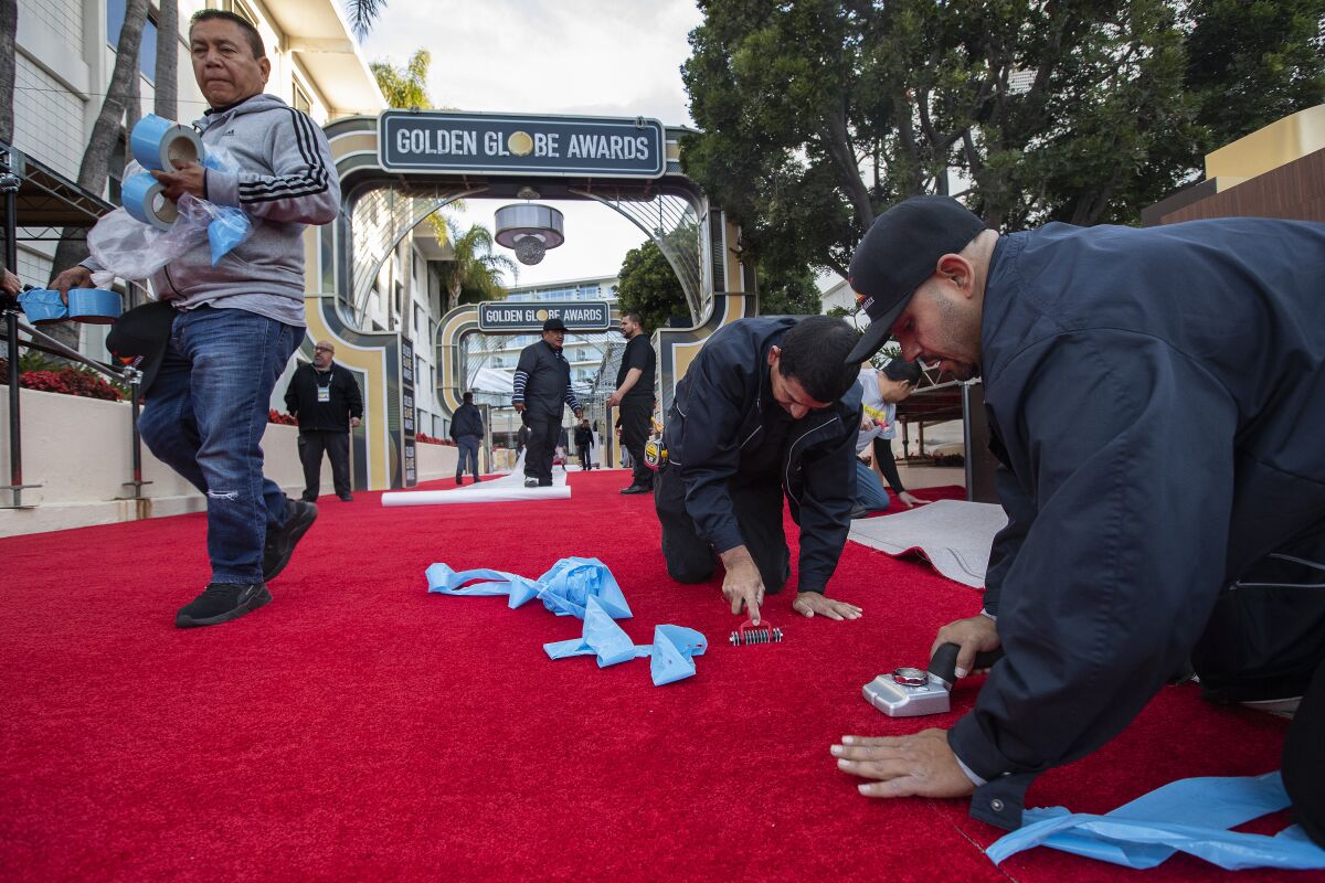 Workers install the red carpet in front of the Beverly Hilton Hotel in Beverly Hills, in preparation for the 77th Annual Golden Globe Awards to be held this Sunday.