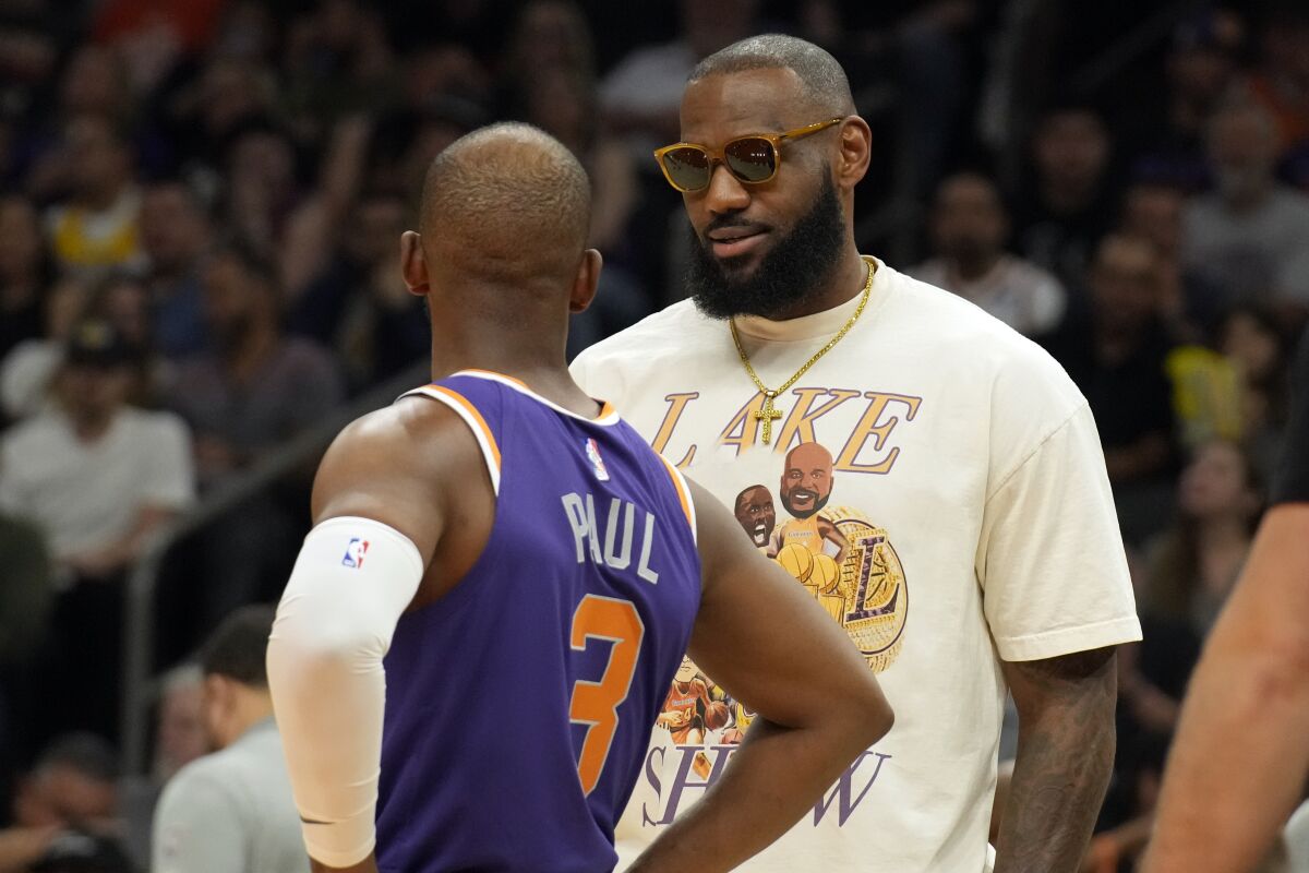 Los Angeles Lakers forward LeBron James talks with Phoenix Suns guard Chris Paul (3) during the first half of an NBA basketball game Tuesday, April 5, 2022, in Phoenix. (AP Photo/Rick Scuteri)