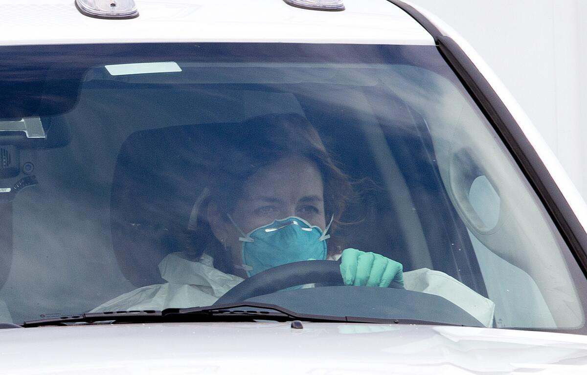 A woman in protective clothing drives an ambulance after departing Dobbins Air Reserve Base in Marietta., Ga. en route Emory University Hospital in Atlanta.