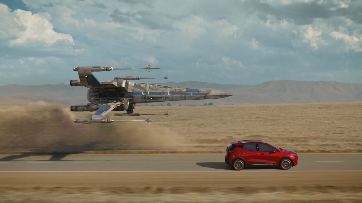 An X-wing from the "Star Wars" universe flies alongside a Bolt EUV in a Chevrolet electric vehicle ad.