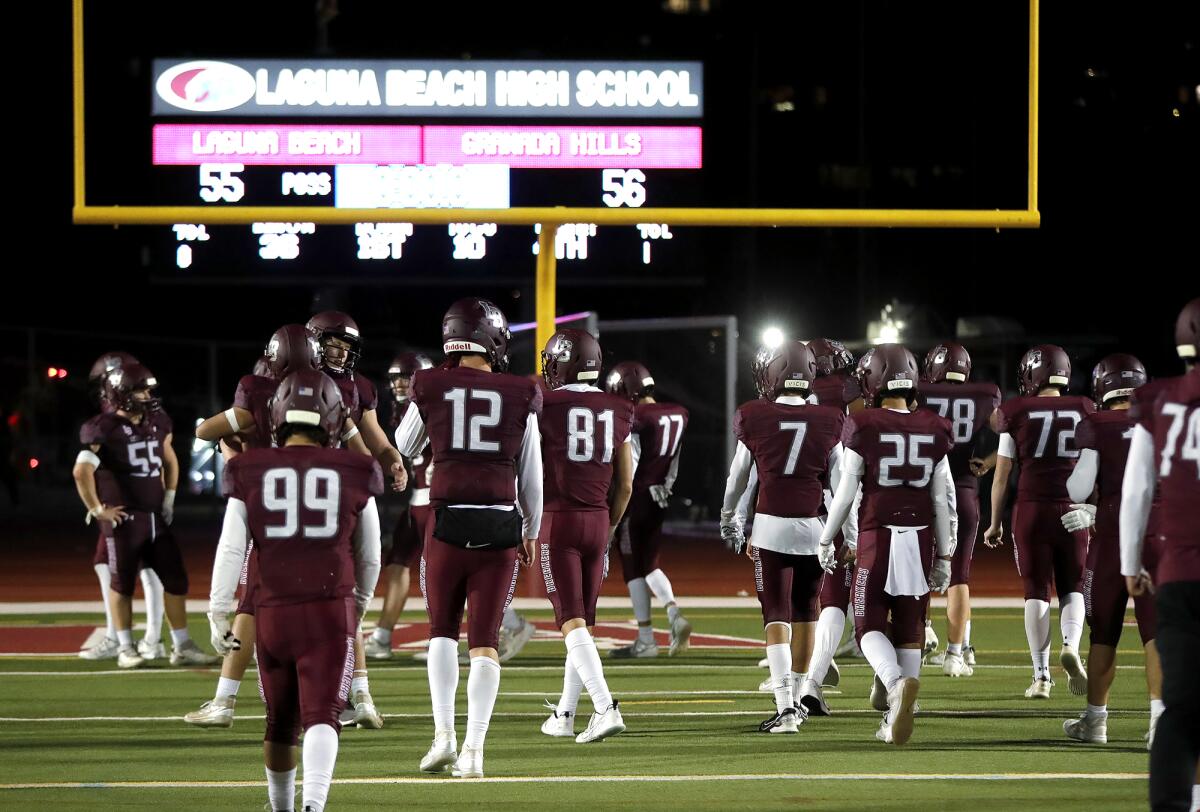 Laguna Beach players walk to the end zone near the scoreboard after the regional final against Granada Hills on Saturday.