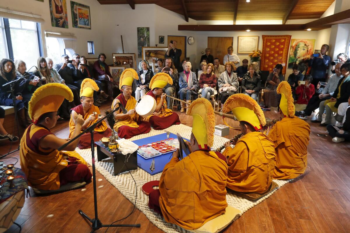 Tibetan monks perform with traditional instruments during an opening ceremony for the creation of the White Tara Mandala.