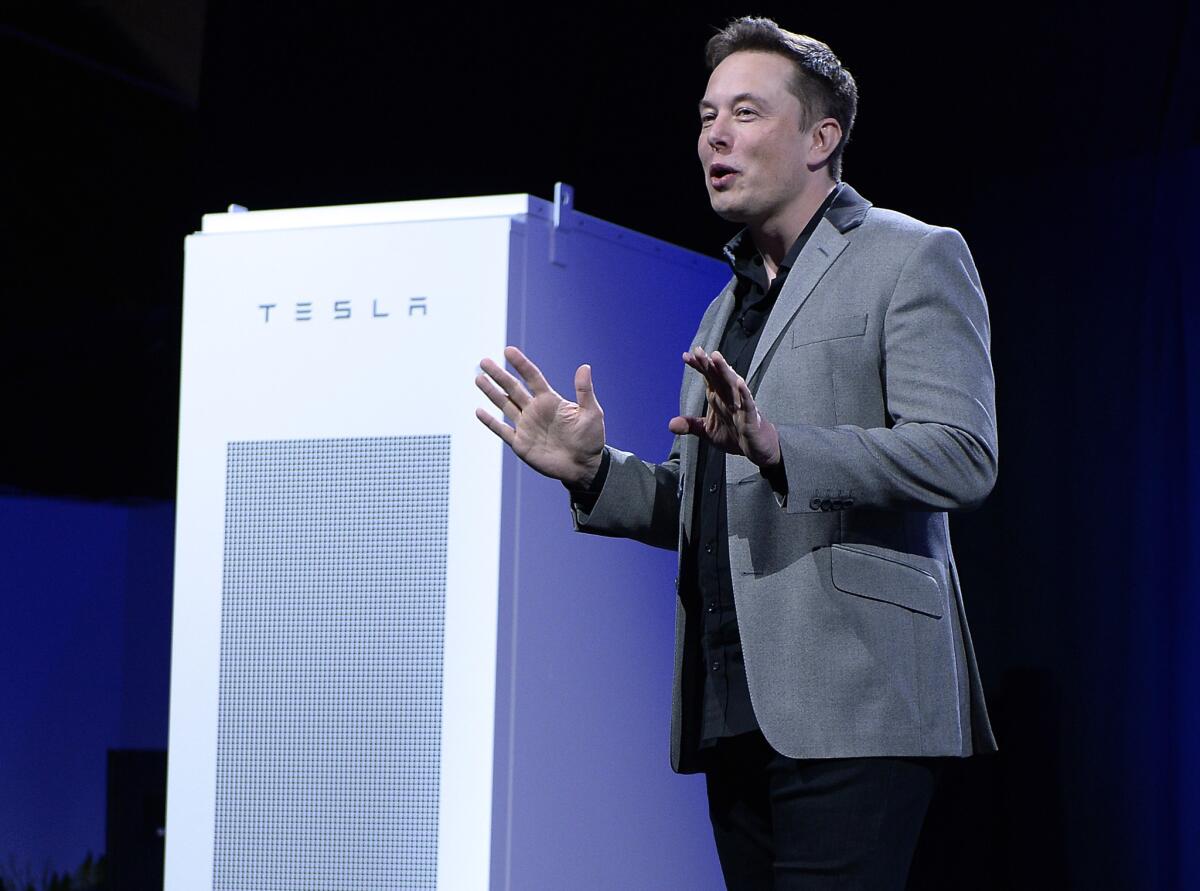 Elon Musk, CEO of Tesla, with a Powerpack -- a battery system that can let businesses store large amounts of energy -- in the background at the Tesla Design Studio in Hawthorne in April. Musk is expected to make a presentation today at Tesla's annual meeting.