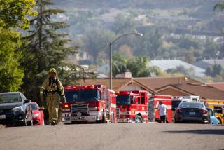 A firefighter walks in a Santee neighborhood off Mast Boulevard near where a brush fire started on Thursday, Nov. 25, 2021.