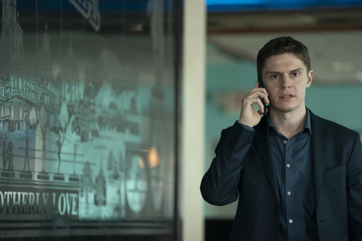 Actor Evan Peters talks on his cell next to a "City of Brotherly Love" mural in a scene from "Mare of Easttown."