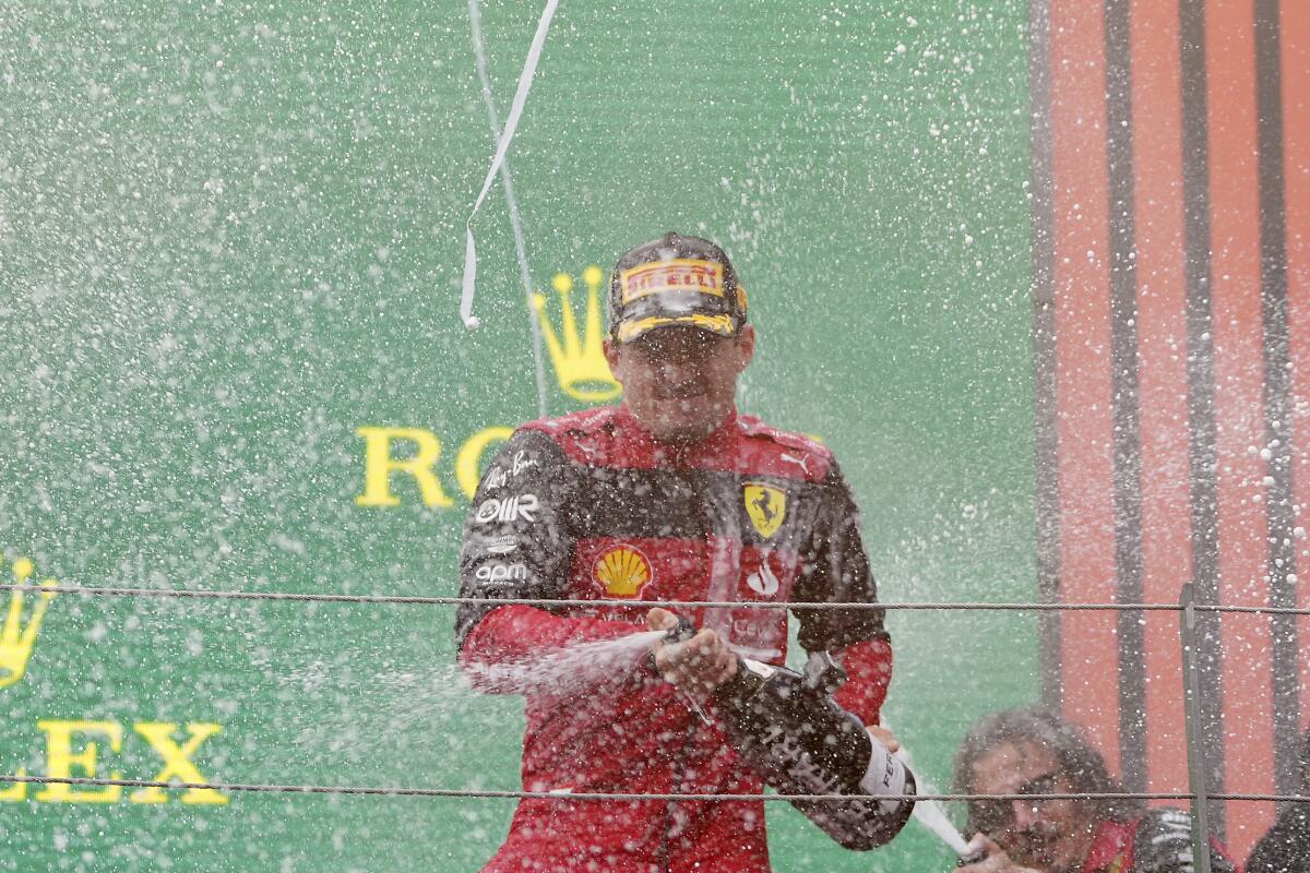 Ferrari driver Charles Leclerc pops open a bottle that sprays liquid.