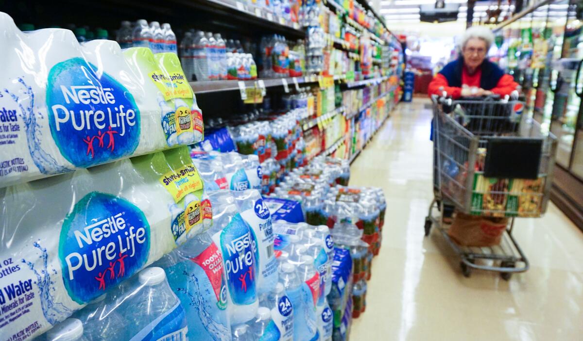 Packages of water bottles stacked on a store shelf.