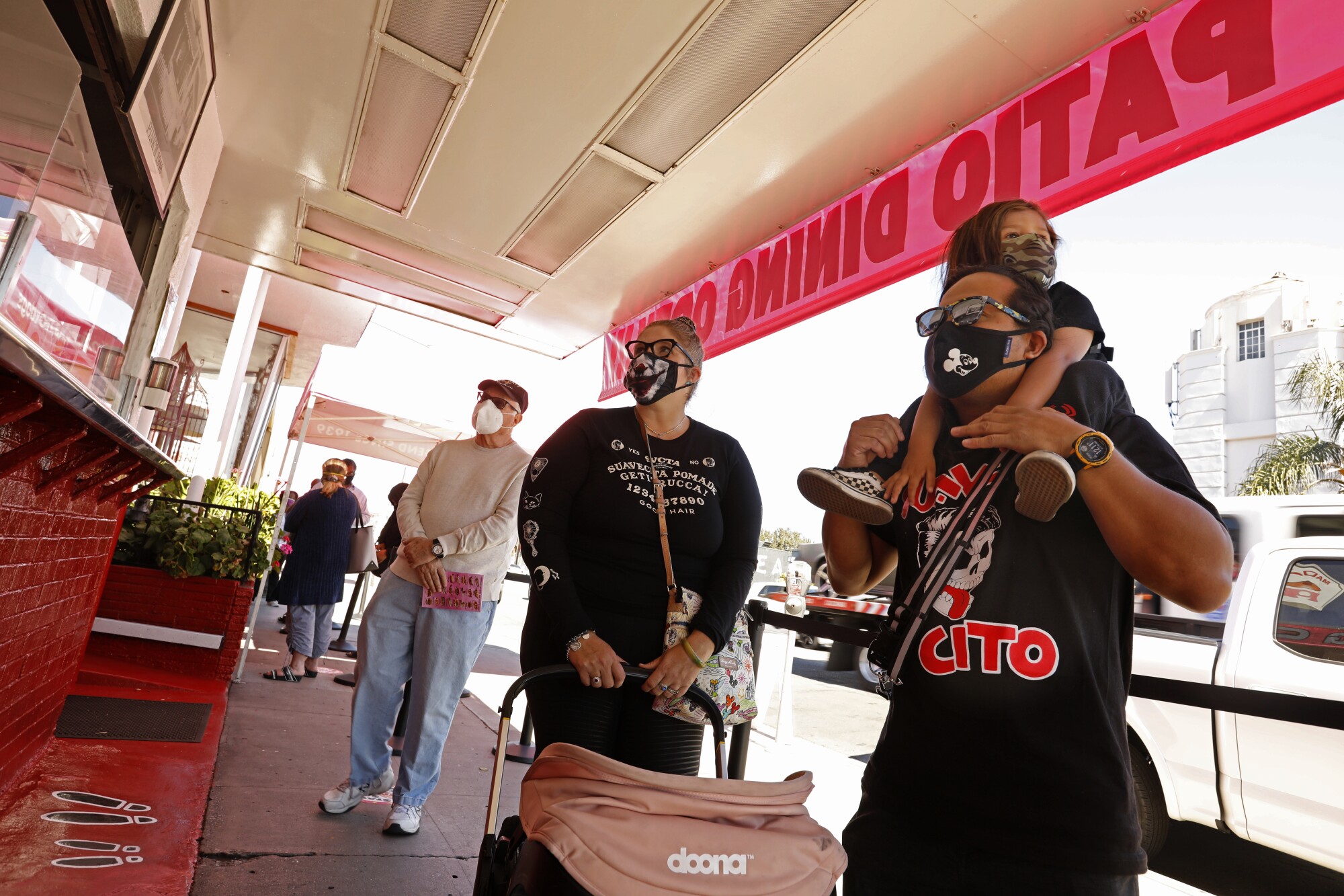 Khder Hernando, right, with his son Xavier, age 3, wait in line at Pink's Hog Dogs