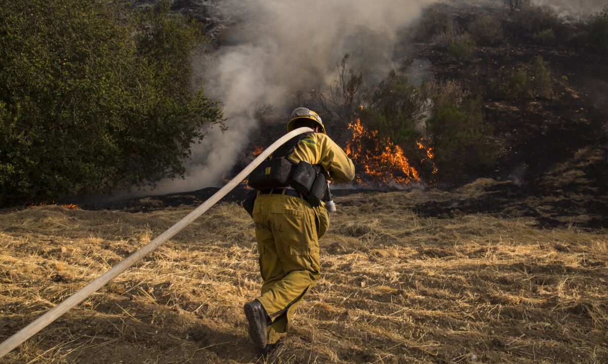 A firefighter rushes to battle flames as brush fires broke out in the Calabasas and West Hills areas.