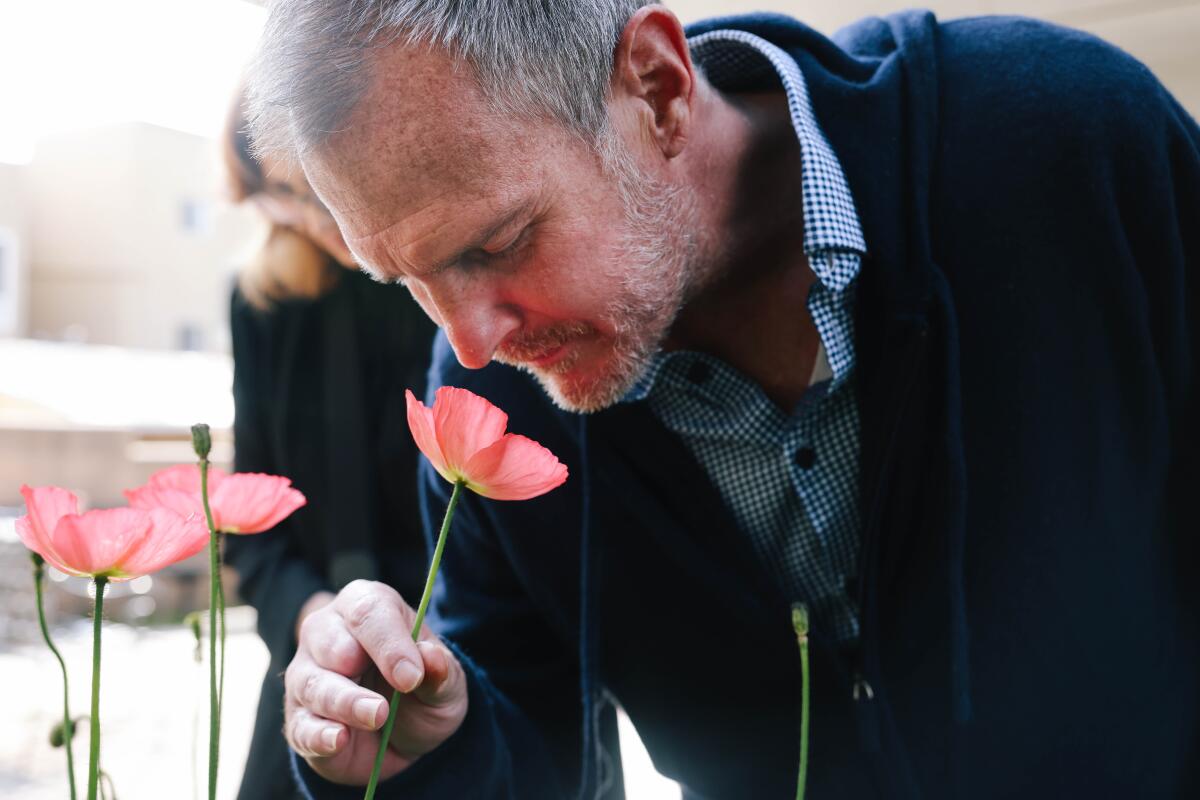 John Maurer smells a flower in the garden outside the board and care home in Hollywood.