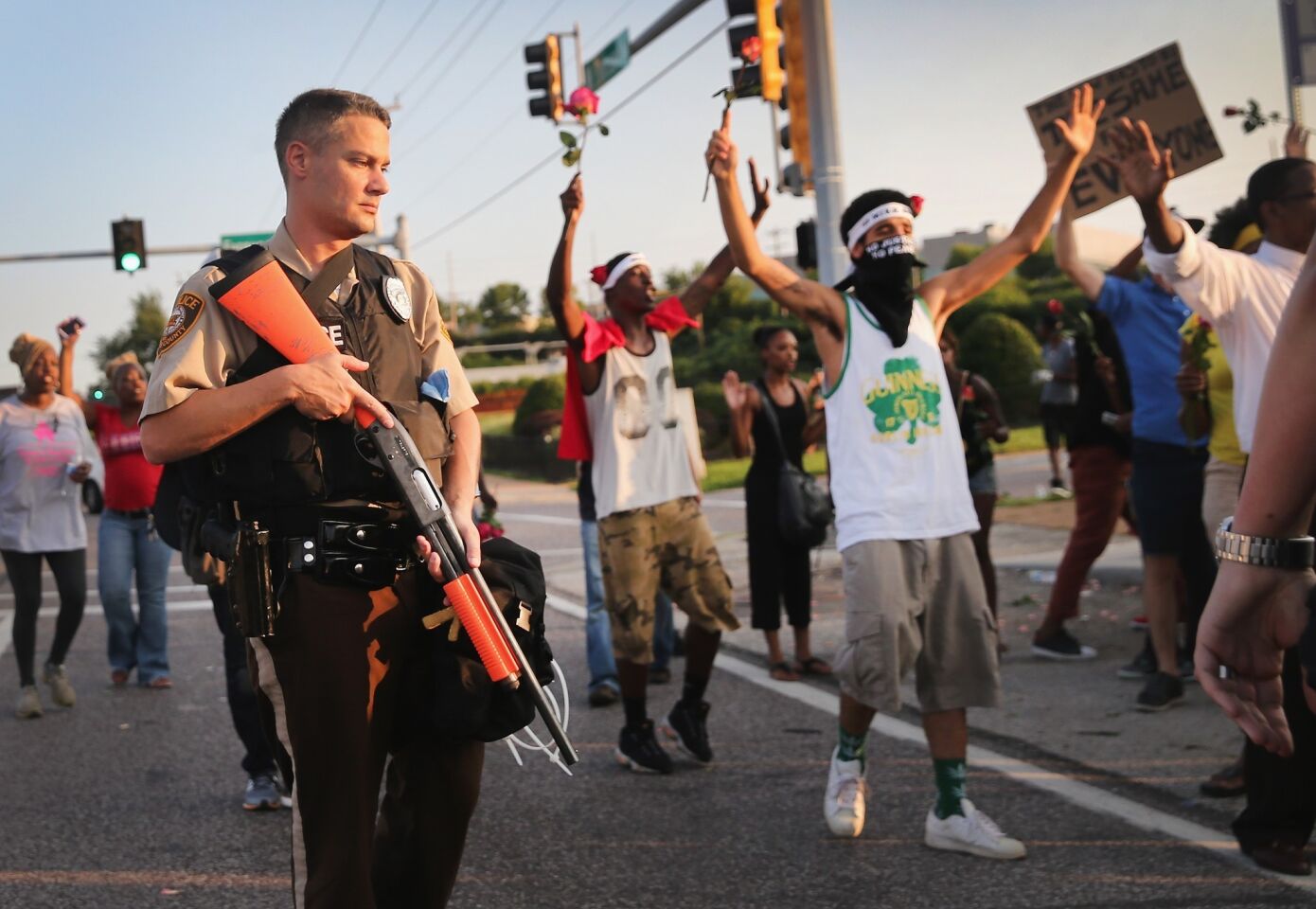 A policeman stands by as demonstrators march in Ferguson on behalf of Michael Brown.