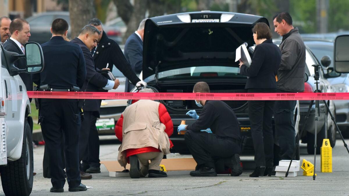 LAPD personnel investigate a shooting by police on 99th Street near South Figueroa Street on Monday morning. The wounded man was treated at a hospital and later charged with attempted murder.