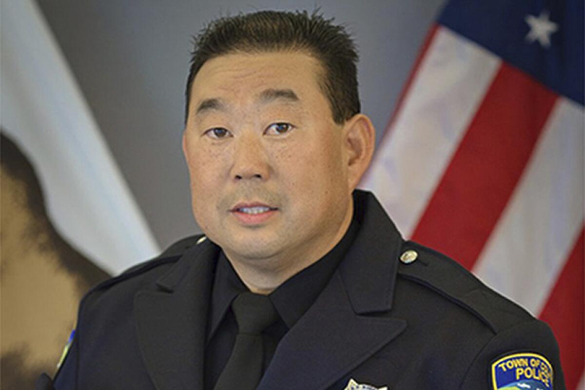 A man with short dark hair in a dark uniform with dark tie 