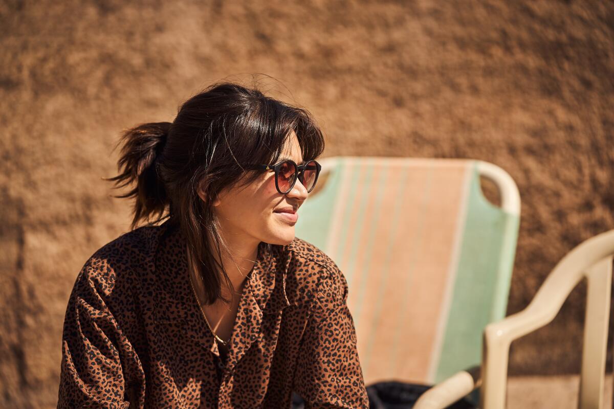 A woman in sunglasses sits outside.