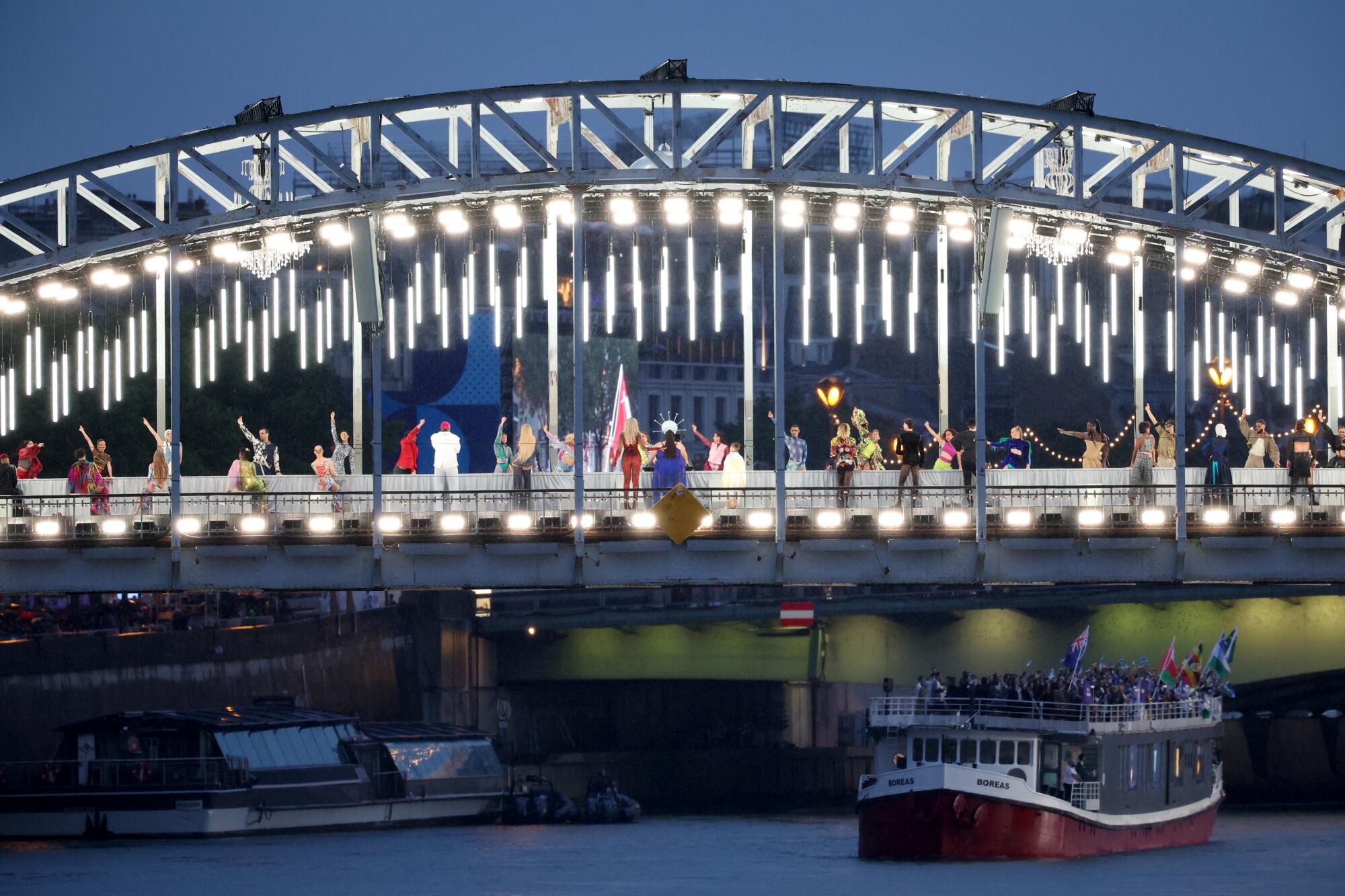 Performers on a catwalk erected along the Passerelle Debilly bridge on the Seine.