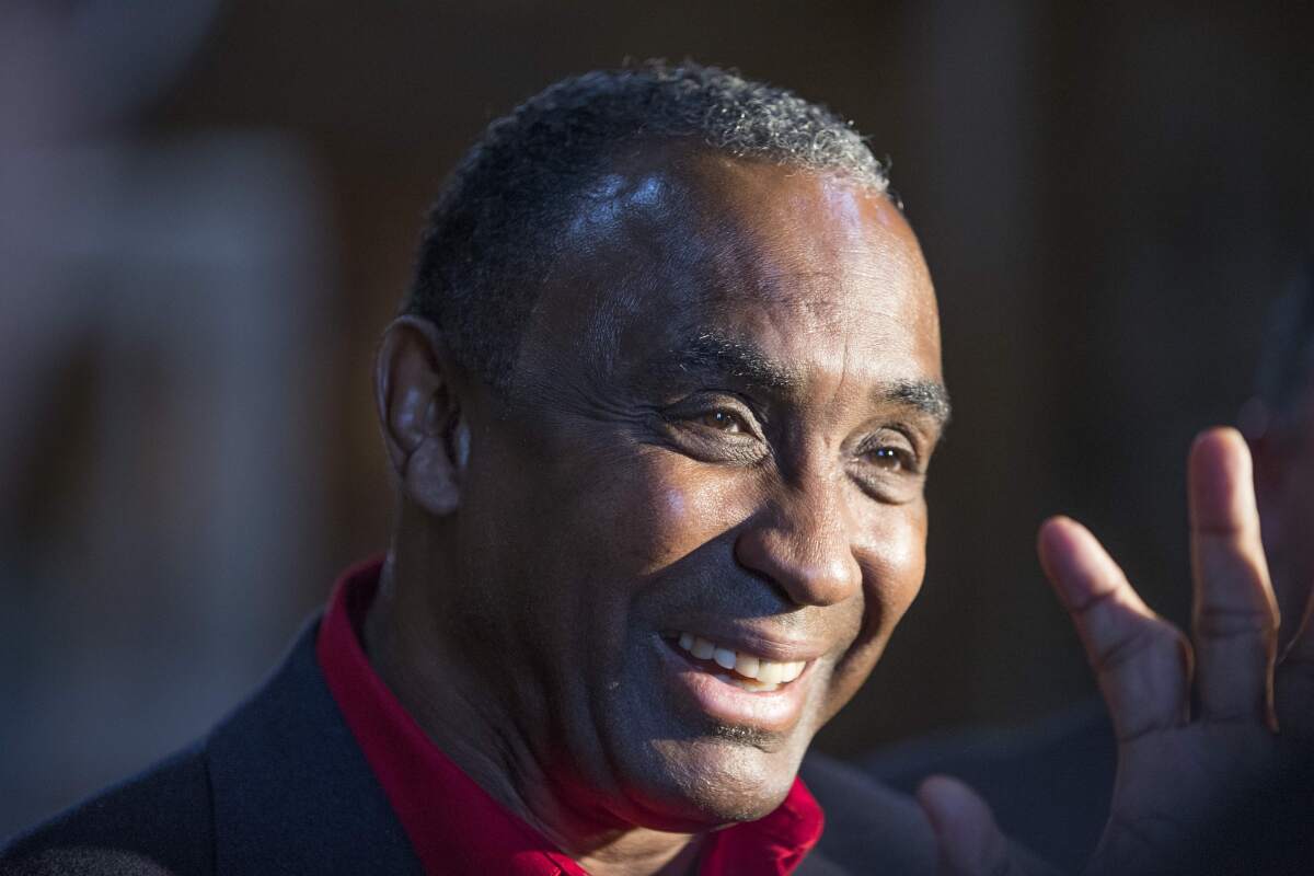 FILE - Johnny Rodgers, the 1972 Heisman Trophy winner, smiles and waves to a well-wisher after he was granted a pardon for his felony conviction for robbing a gas station in 1970, at a state board of pardons hearing Thursday, Nov. 14, 2013, in Lincoln, Neb. Rodgers, the 1972 Heisman Trophy winner and a member of the College Football Hall of Fame, is in an Omaha hospital intensive care unit with COVID-19. (AP Photo/Nati Harnik, File)