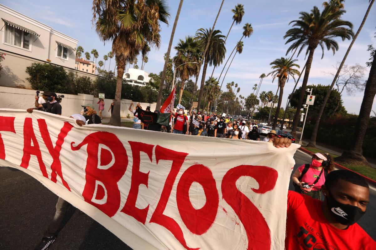 Protesters hold a banner that says "Tax Bezos" and march to Amazon CEO Jeff Bezos' Beverly Hills house.