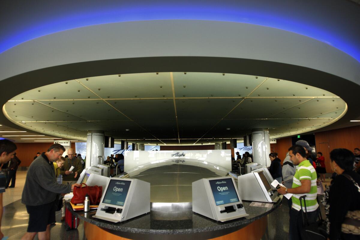Passengers check in at new kiosks for Alaska Airlines at Los Angeles International Airport. Airlines and airports are expected to invest heavily in technology in the next three years, according to a new survey.