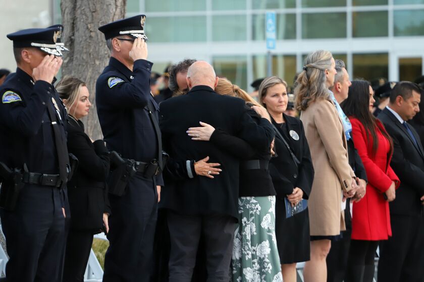 The family of Huntington Beach Police Officer Nicholas Vella hug one another as officer Vella's name is added to the memorial wall during the Orange County Sheriff's Advisory Council annual Peace Officer's Memorial, honoring and remembering the county's 54 fallen peace officers at the Orange County Sheriff's Training Academy on Thursday, May 25, 2023. Officer Vella died on February 19, 2022 in a helicopter crash while responding to a call for service. (Photo by James Carbone)