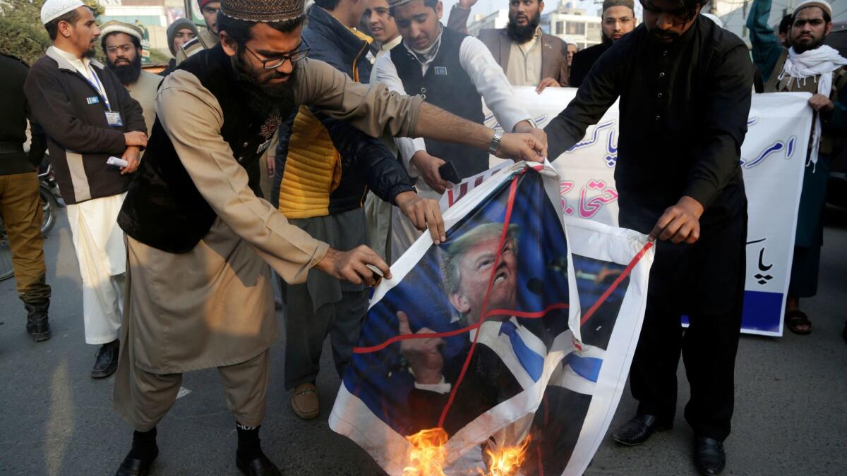 Protesters burn posters of President Trump in Lahore, Pakistan, on Friday.