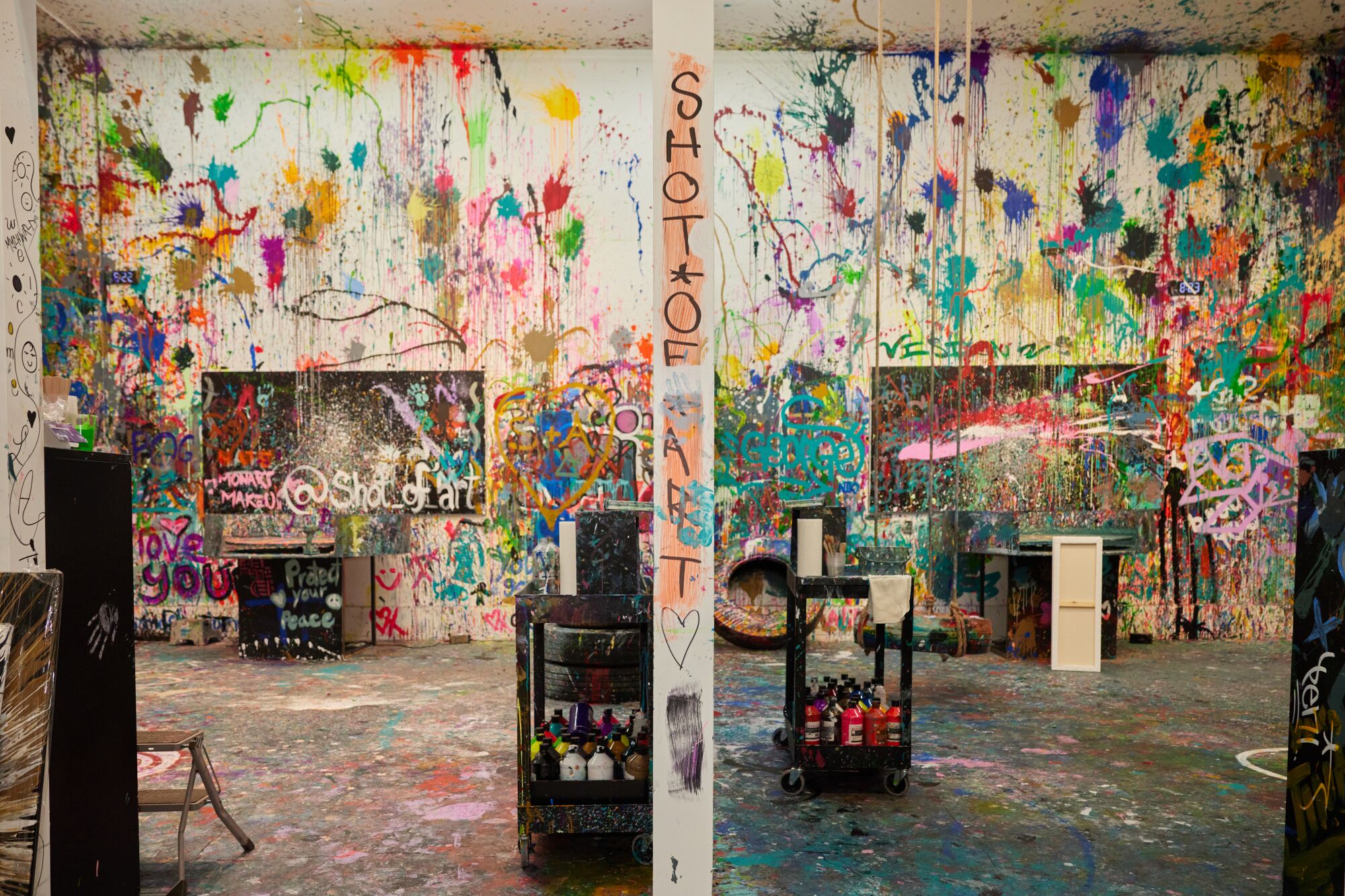 White walls are covered in splatters of multicolor paint.