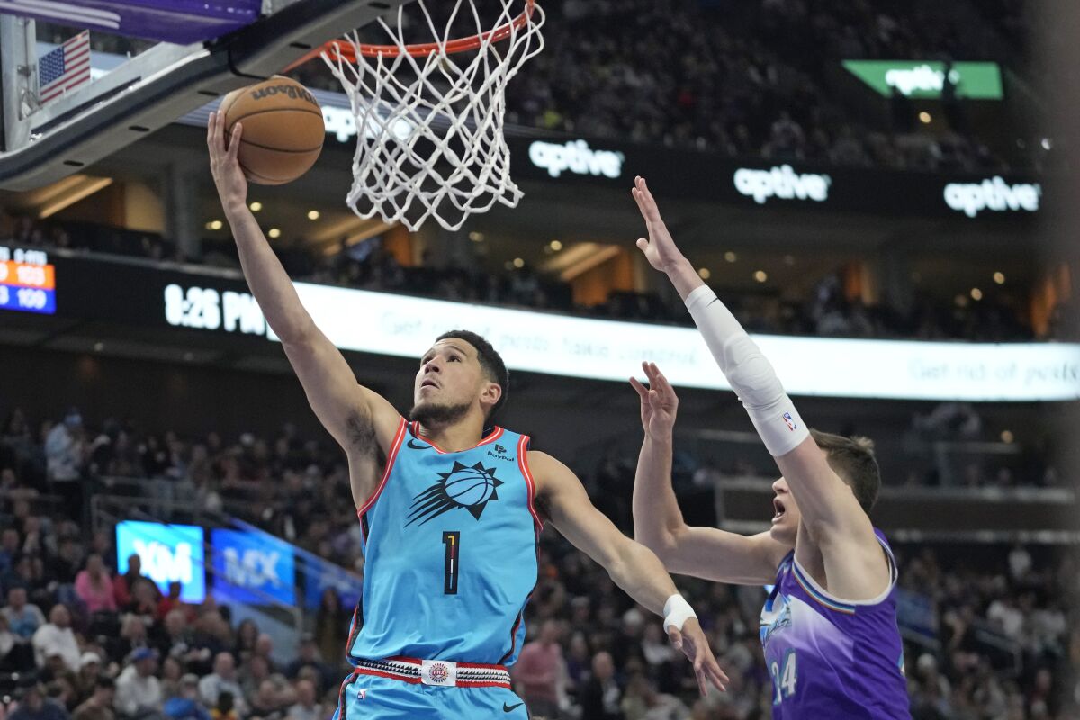 Phoenix Suns guard Devin Booker (1) goes to the basket as Utah Jazz center Walker Kessler (24) defends during the second half of an NBA basketball game Monday, March 27, 2023, in Salt Lake City. (AP Photo/Rick Bowmer)