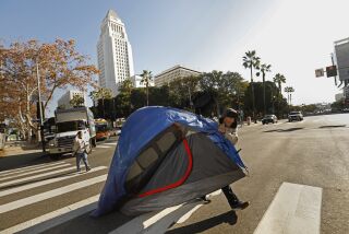 Pasadena, California -Dec. 8, 2022-On Dec. 8, 2022, Eduardo Carmona, age 50, moves his tent across First St. in downtown Los Angeles. City officials were on hand to clear homeless people camped at First St. and Spring St. ahead of the mayoral inauguration. Most all of those camping took an offer to go to the L.A. Grand hotel, which is one of the Project Roomkey hotels. (Carolyn Cole / Los Angeles Times)