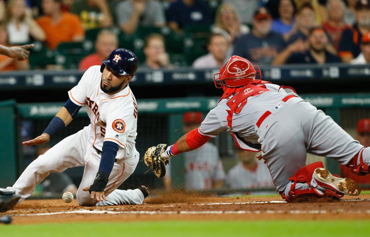 Astros' Marwin Gonzalez (9) slides around Angels catcher Carlos Perez (58), who loses control of the ball in the first inning.