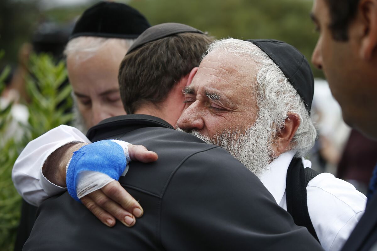 Rabbi Yisroel Goldstein hugs a member of the congregation of Chabad of Poway