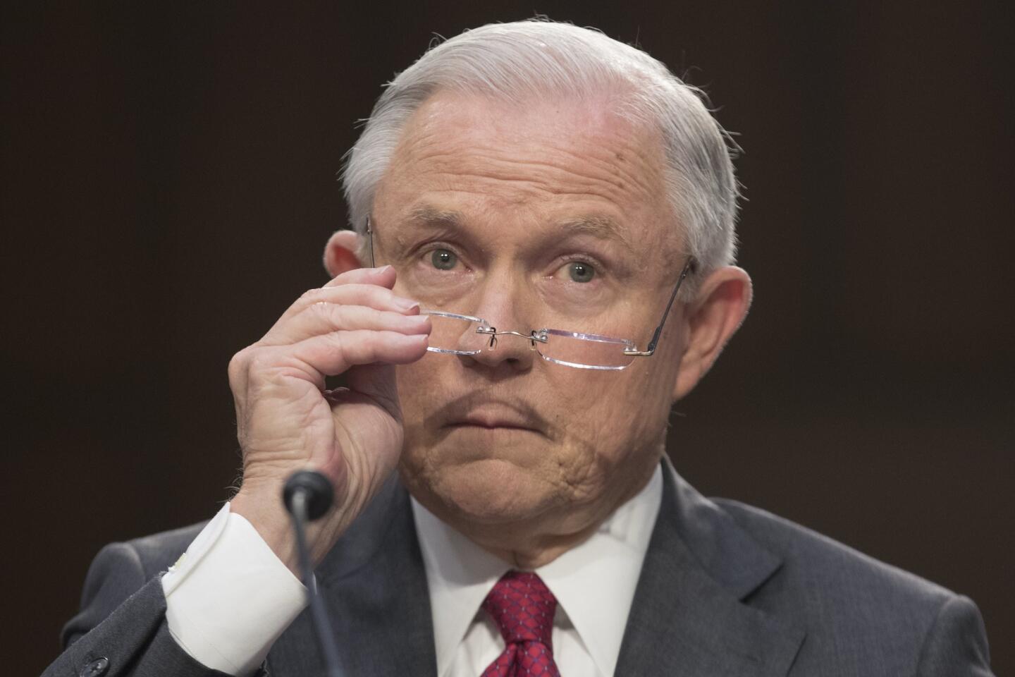 Attorney General Jeff Sessions puts on his glasses while testifying before the Senate intelligence committee on the FBI's investigation into the Trump administration and its possible collusion with Russia during the presidential campaign June 13, 2017.