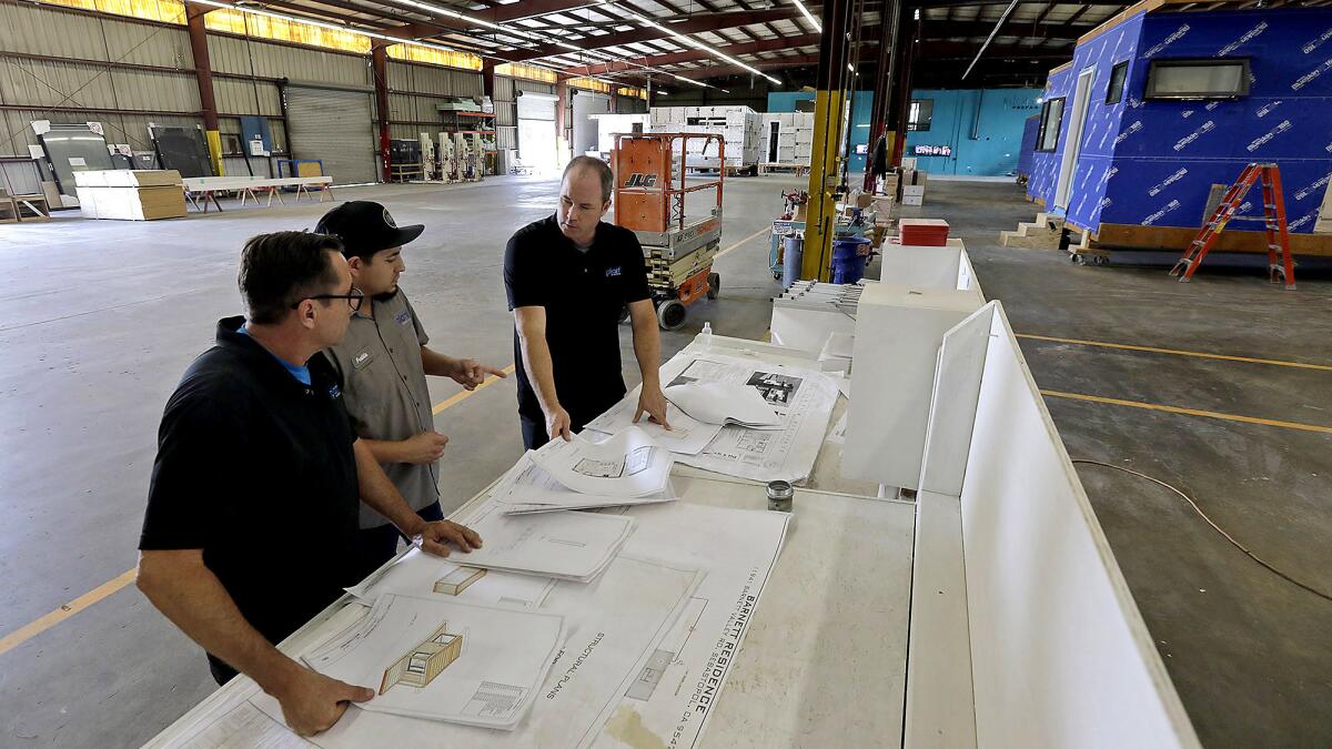 Kevin Allen, right, general manager of Plant Prefab, goes over plans with his staff at the home builder's manufacturing facility in Rialto.