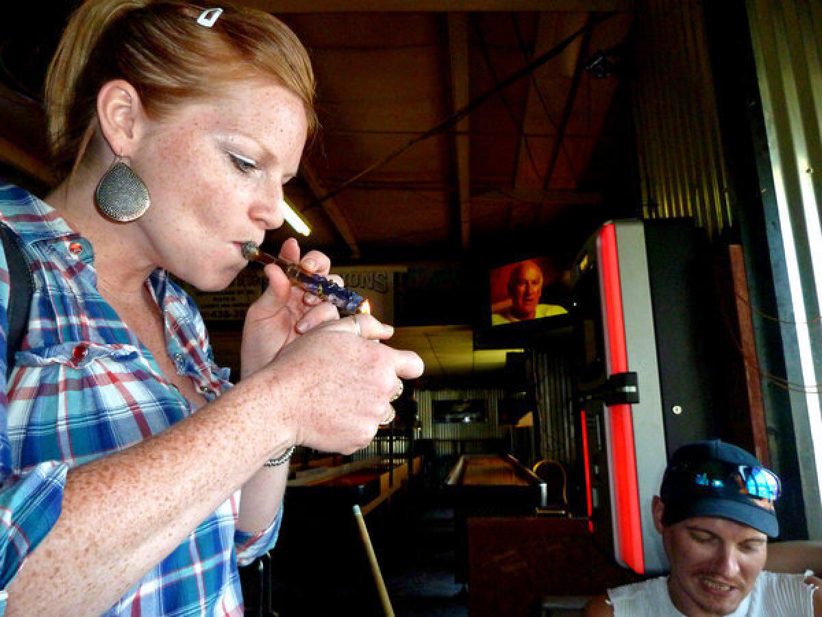 Cassie Hickam smokes marijuana as Jason Southwick sits nearby at Frankie's Sports Bar and Grill. "I'm home," Southwick said. "It's like I'm back in my basement ... Except I'm out in public. Who ever thought we'd see this day?"