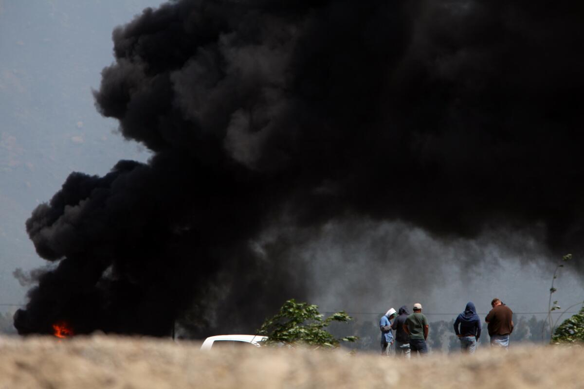Black smoke billows from an agricultural area near Cal State Channel Islands, in Camarillo.