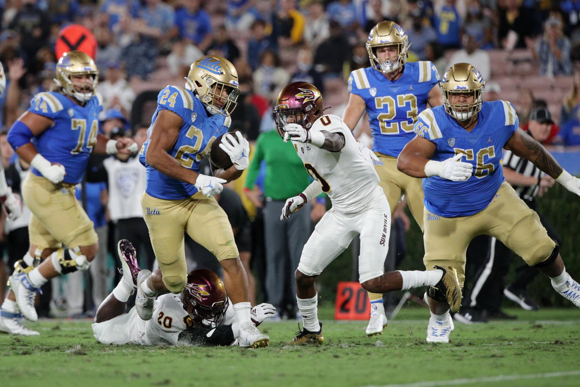 UCLA running back Zach Charbonnet breaks a tackle attempt by Arizona State linebacker Darien Butler.