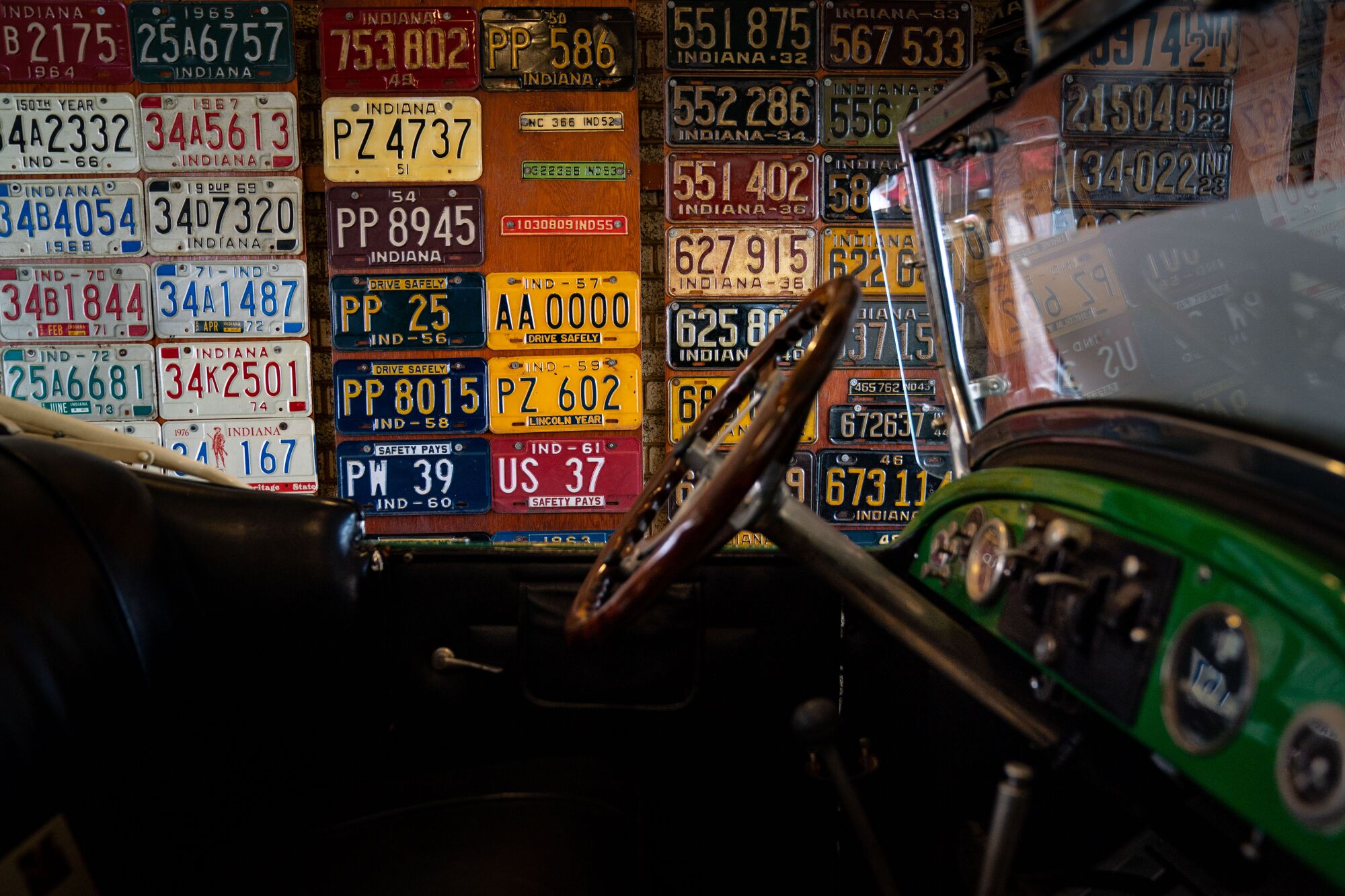 The interior of a vehicle, seen from the side, with a wall of license plates in various colors as the backdrop