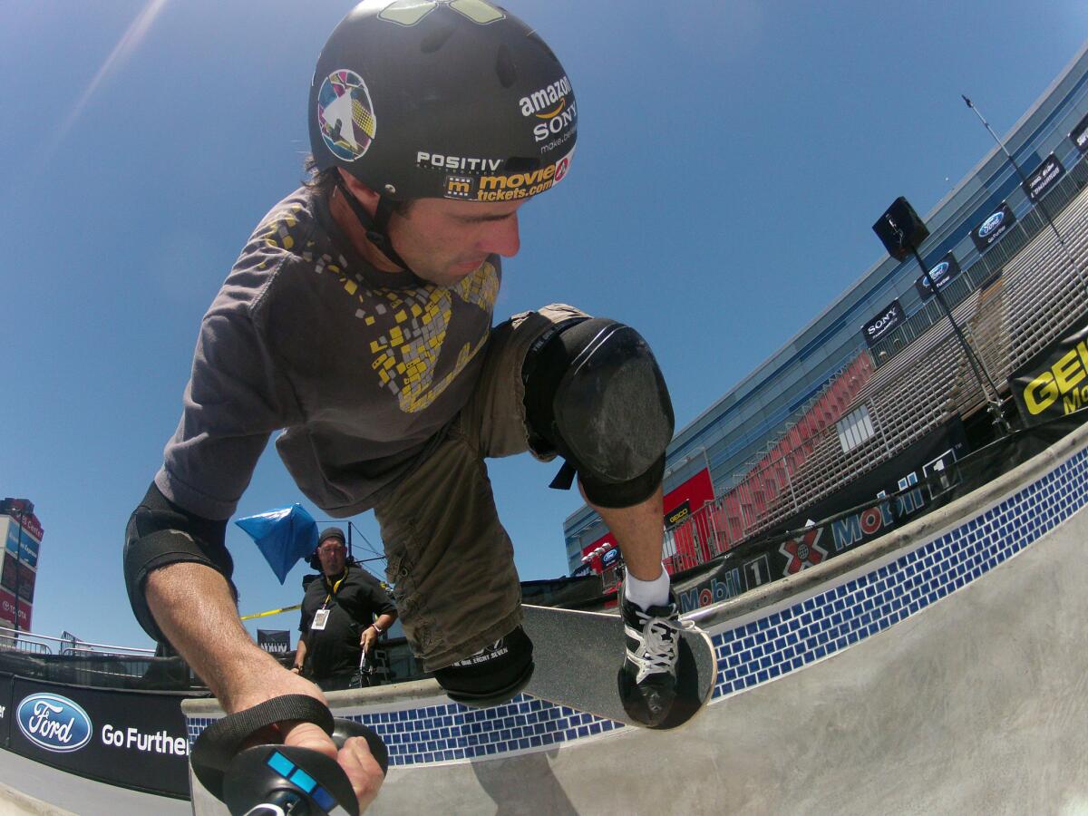 Holding a GoPro camera, pro skateboarder Andy Macdonald grinds across a rail.