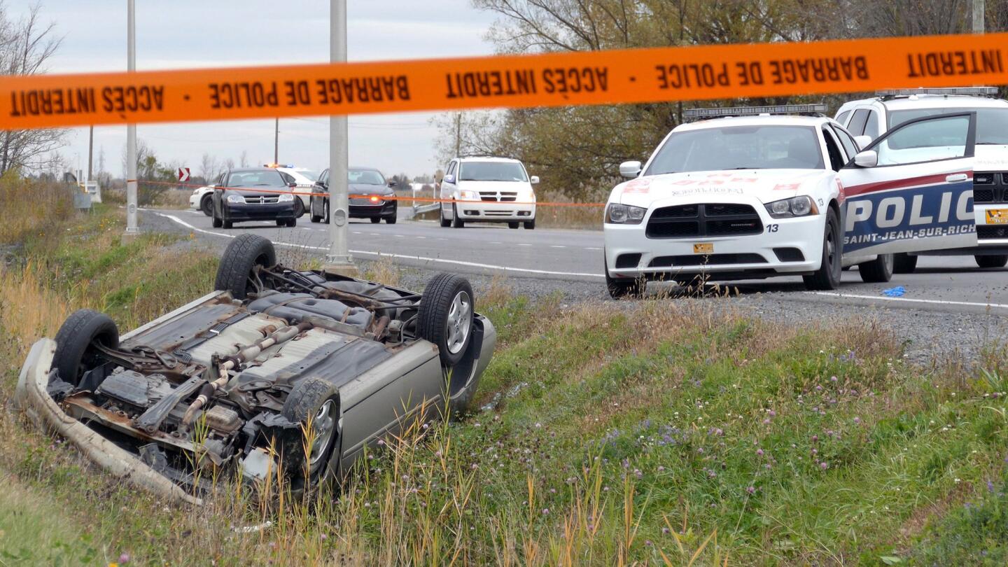 A car is overturned in the ditch in a cordoned off area in Saint-Jean-sur-Richelieu, Canada on Monday. One of two soldiers hit by a car died of his injuries early Tuesday, according to Quebec provincial police.