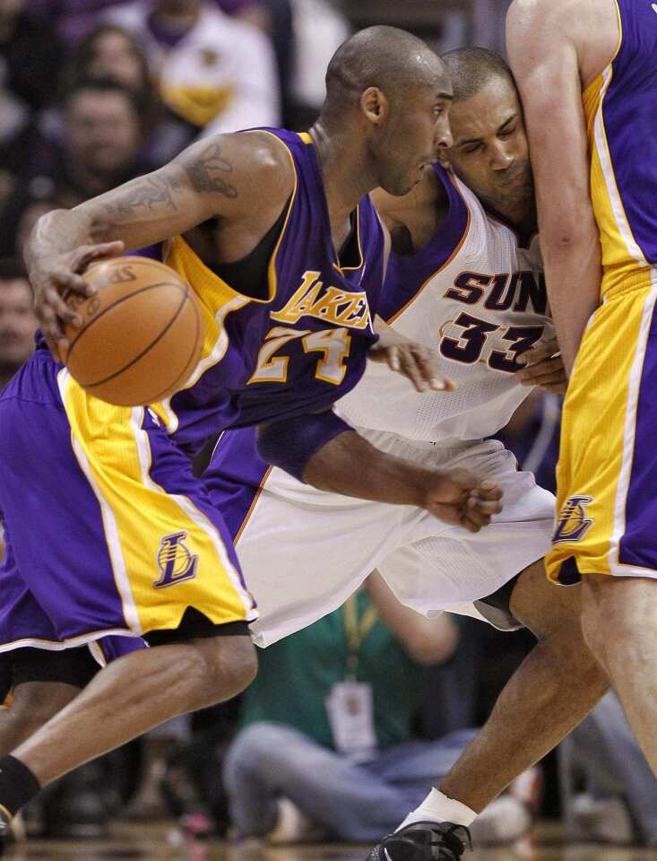 Lakers guard Kobe Bryant uses a screen by Pau Gasol to drive past Suns forward Grant Hill in the second half Sunday at US Airways Center in Phoenix.