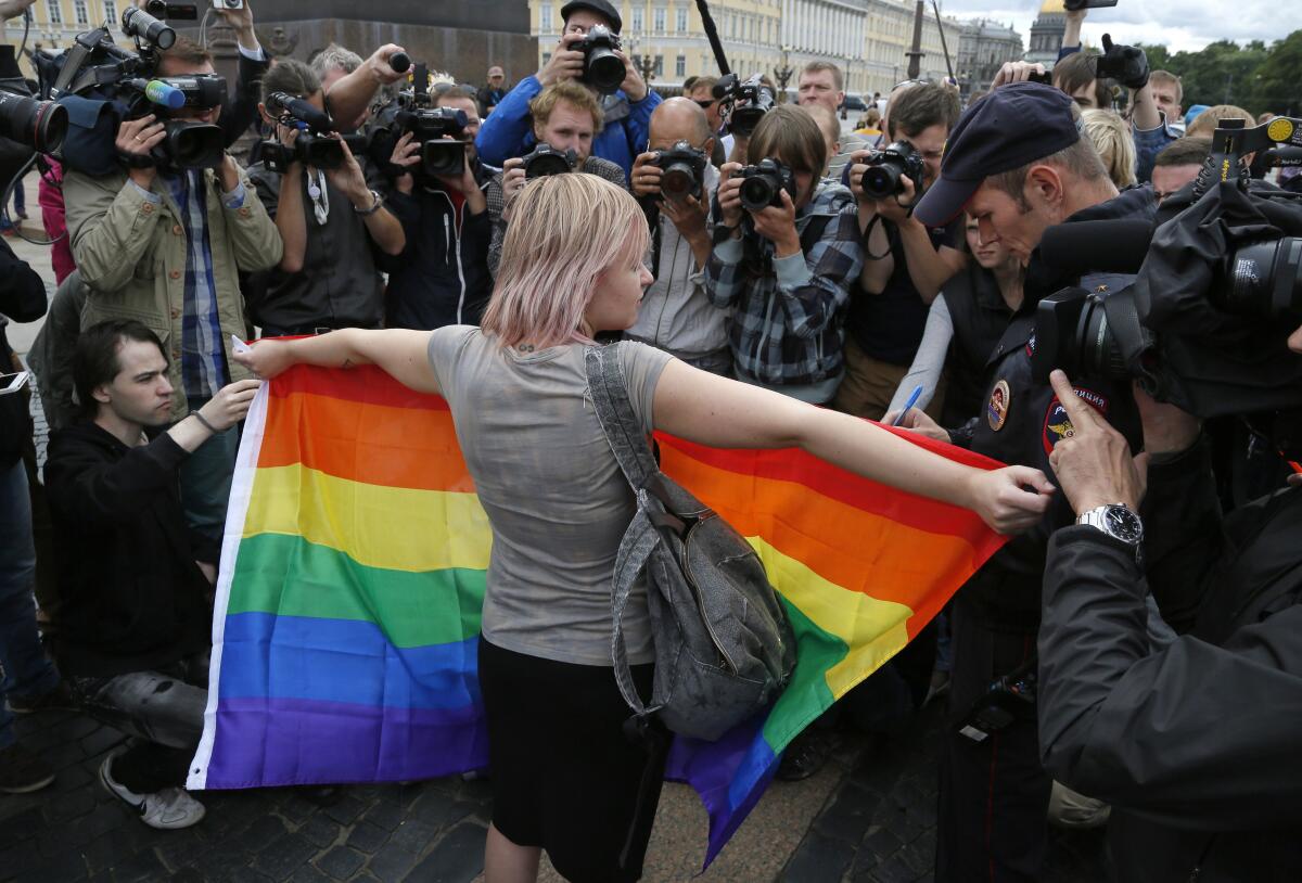 A gay rights activist stands with a rainbow flag, in front of journalists taking her photo, in St.Petersburg, Russia.