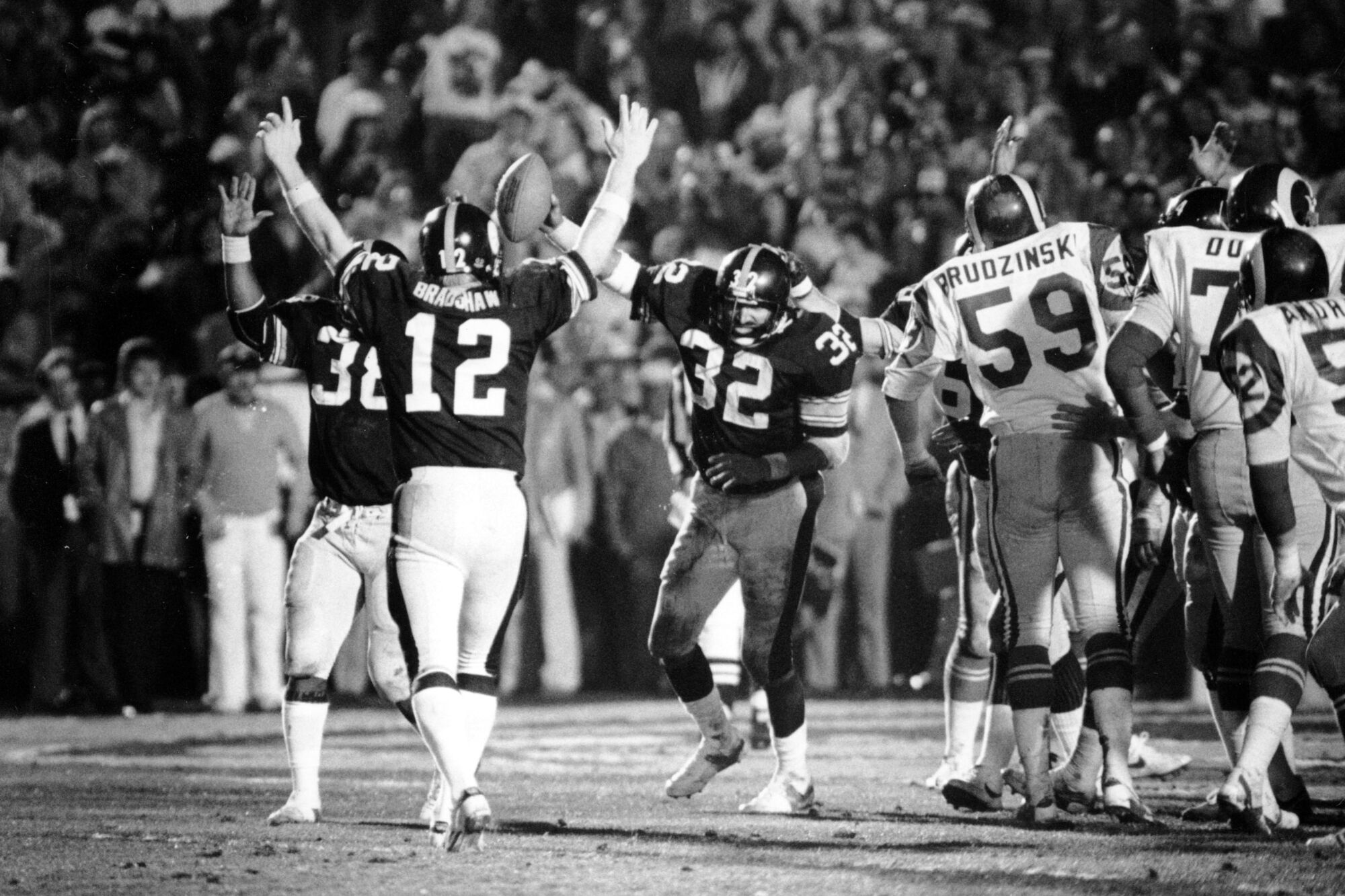 Steelers running back Franco Harris (32) holds up the football as Terry Bradshaw (12) and Sidney Thornton (38) celebrate
