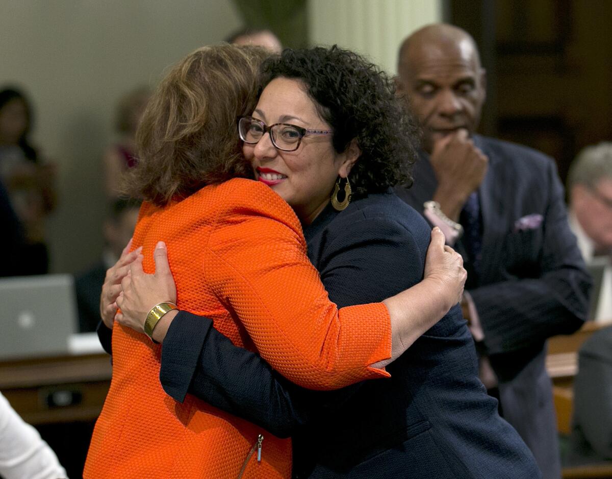 Assemblywoman Cristina Garcia (D-Bell Gardens), right, is congratulated by Assemblywoman Eloise Reyes (D-Grand Terrace) after the vote.